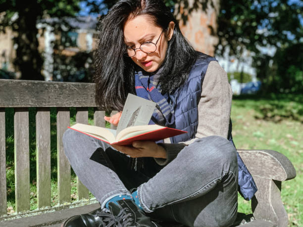 istock Young woman is reading book in park 1386521316