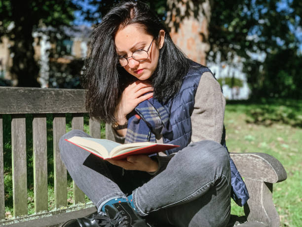 istock Young woman is reading book in park 1386521317