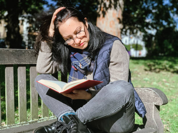 istock Young woman is reading book in park 1386521321