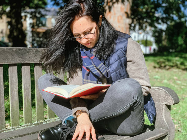 istock Young woman is reading book in park 1386521336