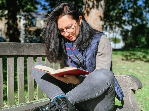 istock Young woman is reading book in park 1386521340