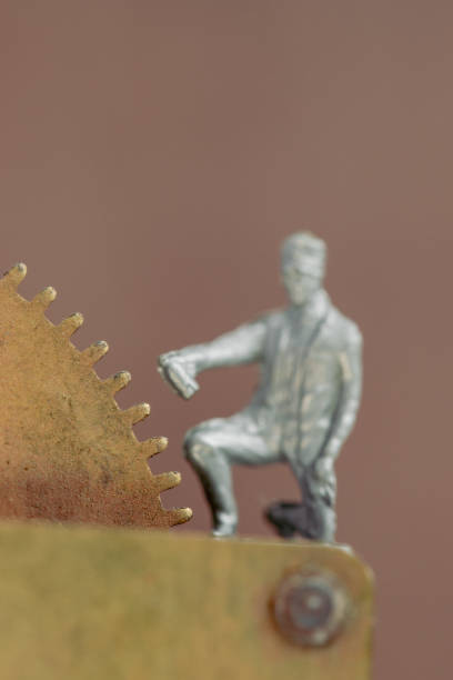 Macro of clock parts with a old cast iron railroad worker in background