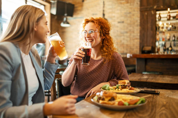 Female Friends having a beer Happy Female Friends Having meal And Beer And Laughing women only restaurant stock pictures, royalty-free photos & images