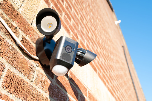 A closed circuit TV camrea mounted on an inner-city weathered brick wall in London, England.