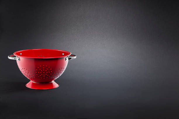 istock Stainless steel red colander on black background 1386523542