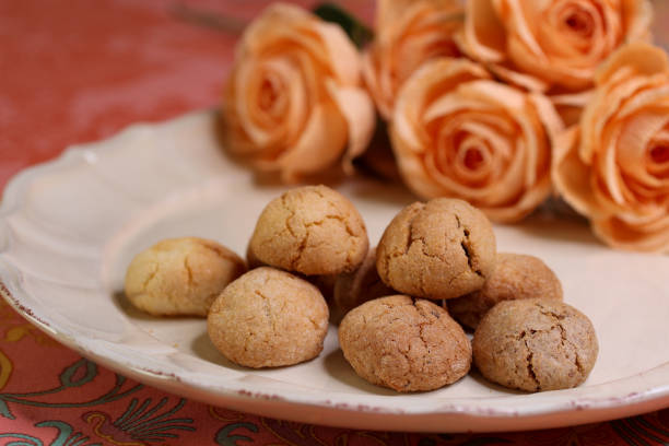 visão próxima de biscoitos amaretti caseiros perto de rosas laranja - cake afternoon tea italian culture biscotti - fotografias e filmes do acervo