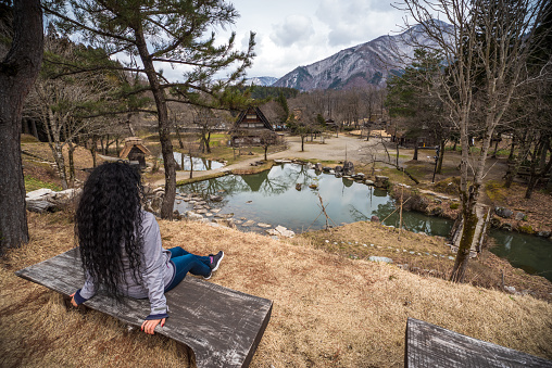 Tourist woman seated in front of Shirakawa-go village pond