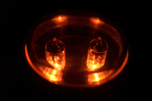 Two glowing electronic tube in modern pre amplifier, on black background