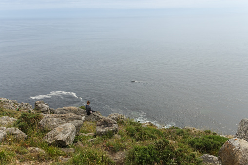 2018 June 25. Spain. Fisterra. Lonely pilgrim look at the vastness of the Atlantic Ocean