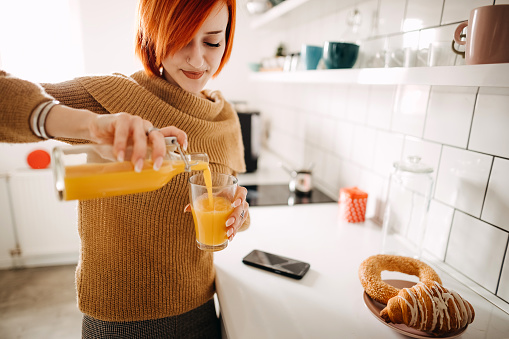 Young  woman preparing orange juice at the kitchen