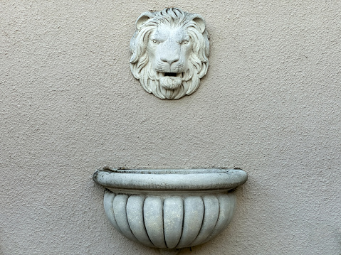 A lion head with a ring in its mouth as a decoration on an iron vase against the other vases.