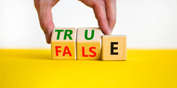 istock False or true symbol. Businessman turns wooden cubes and changes the word false to true or vice versa. Beautiful yellow table, white background, copy space. Business and false or true concept. 1386532055