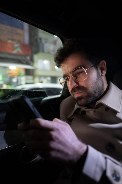 istock Businessman sitting in car and using phone 1386532274