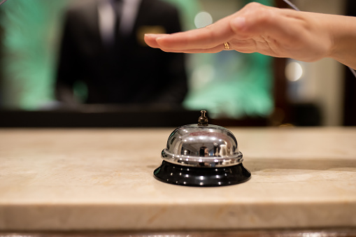 Woman ringing bell on hotel reception desk