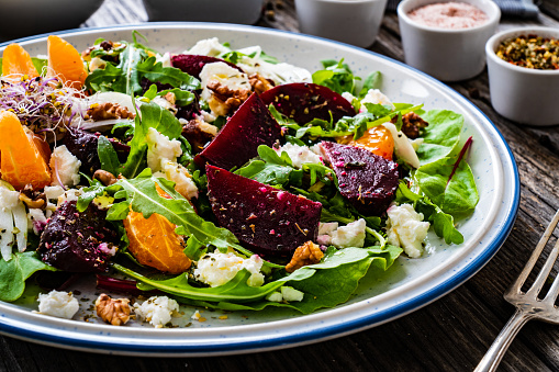 Beets salad with goat cheese mandarin and walnuts on wooden background