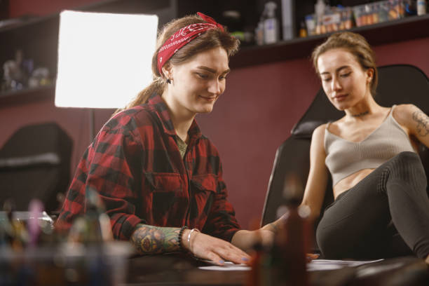 istock Woman tattoo artist smiling while working with client 1386537680
