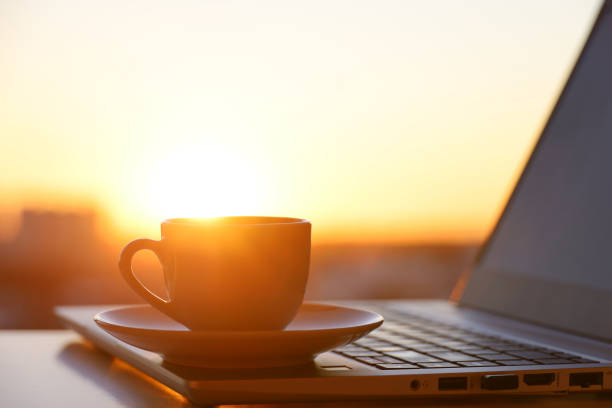 istock Coffee or tea cup on laptop against the window with sunshine 1386540017