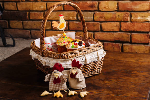 Easter basket with ukrainian easter cake, cookies and Easter eggs on a wooden desk. Easter chicken figures