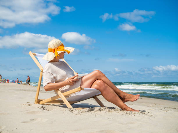 istock Woman relaxing on beach reading book 1386543763