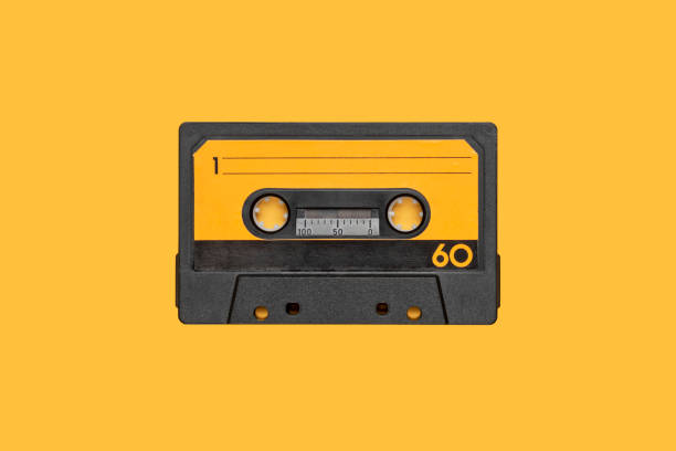 VINTAGE CASSETTE AUDIO TAPE LOOP ISOLATED ON ORANGE BACKGROUND VINTAGE CASSETTE AUDIO TAPE LOOP ISOLATED ON ORANGE BACKGROUND yellow tape audio stock pictures, royalty-free photos & images