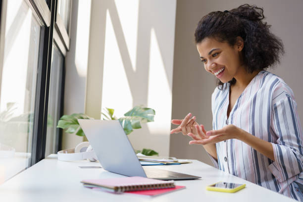 istock African American businesswoman using laptop computer having video call sitting in modern office. Young freelancer working online from home, discussion something 1386559571