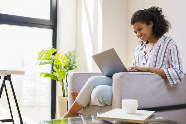 istock Freelancer copywriter working from home. Happy confident African American woman using laptop computer, communication online, sitting on sofa. Student studying, distance learning 1386559689