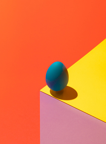Modern optical illusion made of Easter egg on colorful background. 3D render blue egg on paper cube. Abstract Easter composition.