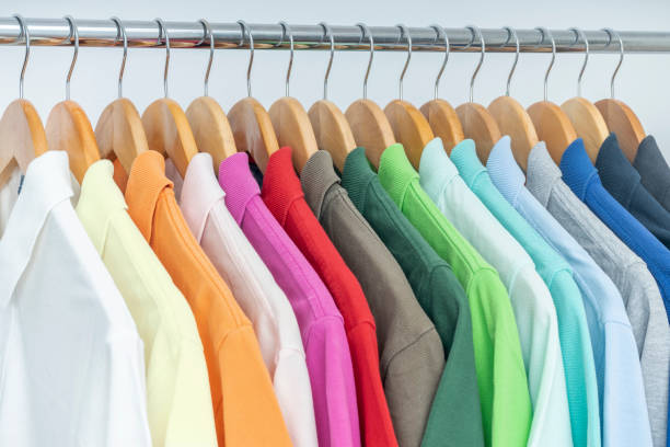 organizadas camisas polo coloridas penduradas no rack, armário, guarda-roupa, camarim ou loja. conceito de vendas e compras. coleção de roupas masculinas de verão. - polo shirt multi colored clothing variation - fotografias e filmes do acervo