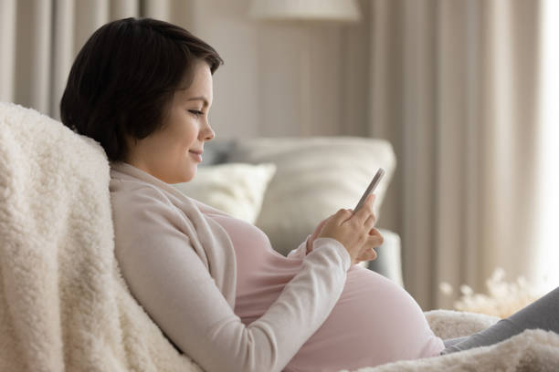 istock Expectant mom watch childbirth video on phone text message 1386572010