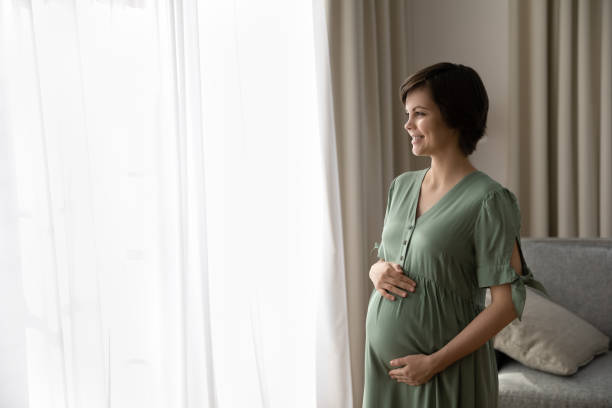 istock Hopeful future mom touch belly look in light window 1386572048