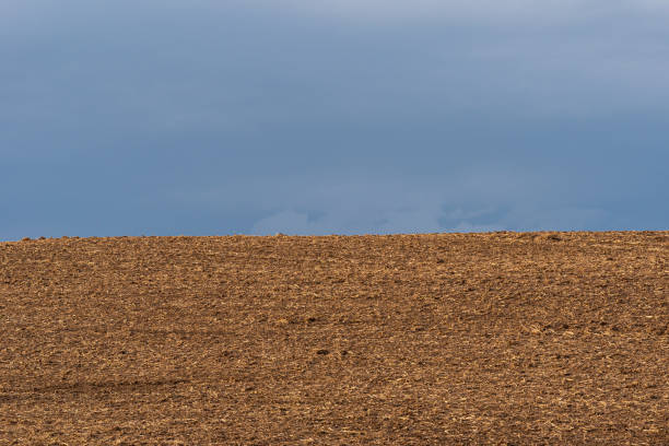 istock Freshly plowed field with an heavy cloudy sky 1386574071