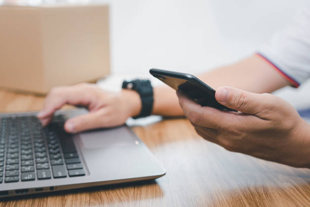 istock Close up hand a parcel delivery staff hold smartphone check parcel delivery information online and input data in laptop 1386576867