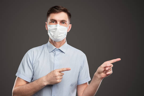 istock Serious man in medical mask pointing away 1386577874