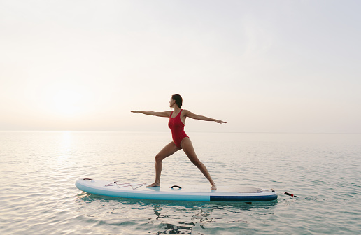 Photo of a young woman practicing yoga and meditation on a paddleboard.