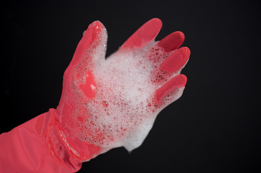 Hand in Soapy Pink Dishwashing Glove, Black Background