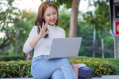 Asian woman publicly uses their laptop to study and work outdoors in shopping malls.