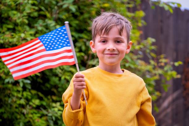 istock Smiling boy waving a US flag looking at the camera 1386603880