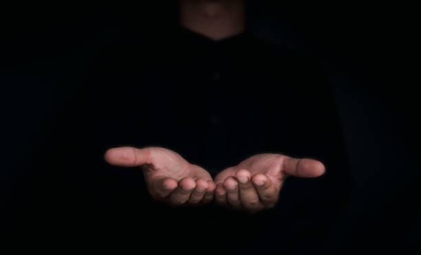 Give two hands with nothing on both on dark background with copy space. Close-up receiving gesture of outstretched cupped empty open hands. Concept of giving, donation, receiving, asking, and bribery.