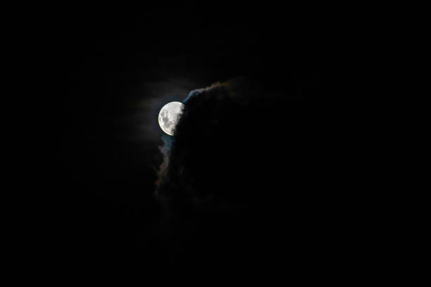 The moon with cloud cover drifting past in the night sky over Woy Woy on the Central Coast of NSW, Australia.