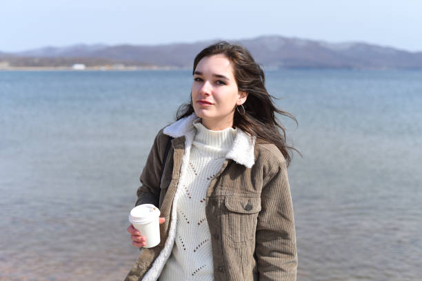 giovane donna russa che beve caffè contro il mare giapponese in primavera - russian ethnicity cold relaxation nature foto e immagini stock