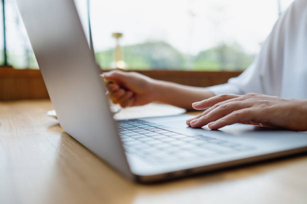 istock Closeup image of a woman drinking coffee while working on laptop computer 1386621284