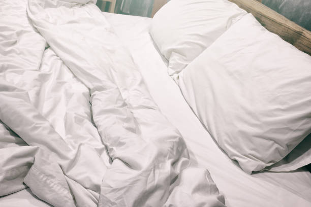 istock Messy white bed and pillow, in the morning 1386623118