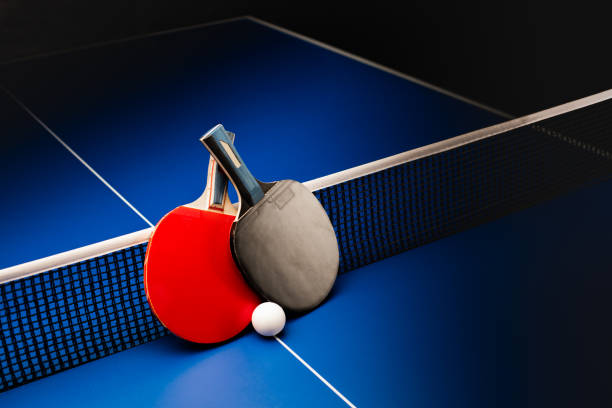 Ping pong rackets and balls on a blue table with net. stock photo