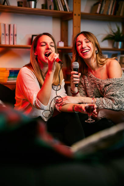 Girls having fun at karaoke night at home. stock photo