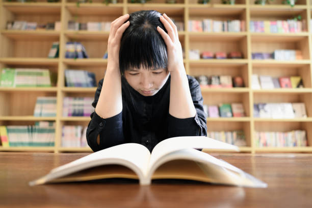 A young Asian woman is reading in The library.