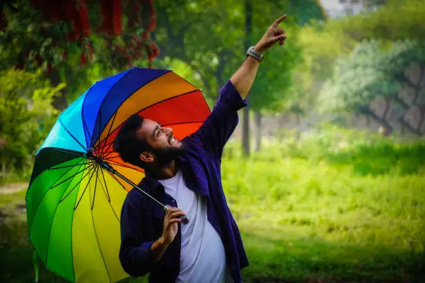 Photo of man with umbrella in spring season with flowers in background