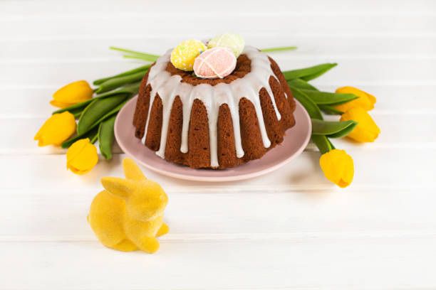 istock Glazed easter cake decorated with mini eggs, yellow tulips and Easter Bunny 1386630851