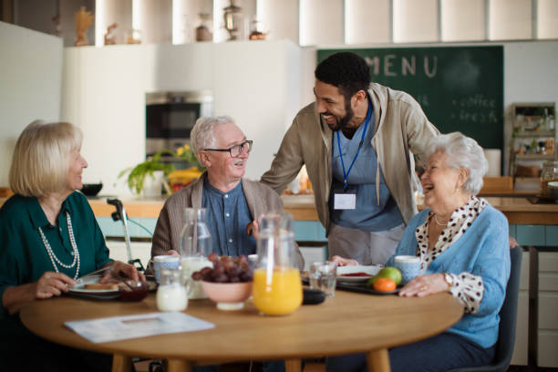 group of cheerful seniors enjoying breakfast in nursing home care center. - ouderenzorg stockfoto's en -beelden