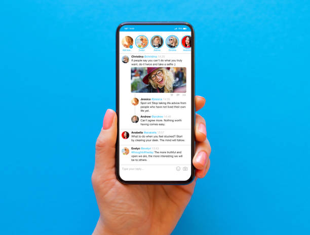 persona che tiene il telefono in mano con un feed di notizie sui social media di esempio sullo schermo - twitter foto e immagini stock