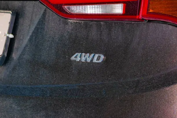 Photo of the 4wd logo on the SUV. Part of the car. Part of the rear bumper and taillight.